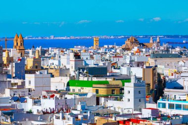 İspanya, Cadiz 'in canlı şehir manzarası modern ve tarihi binaların yoğun bir karışımı. Mimari, arka planda mavi körfez suyunun görülebildiği kilise kuleleri ve diğer tarihi yapıları içerir.