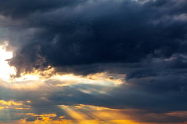 Gökyüzü, ufukta beliren beklenti atmosferini örten karanlık ve ağır bulutlarla doludur. Yoğun oluşumlar, her şeyi sessiz ve kasvetli bir ışıkla kaplayan gölgeli bir renge bürünür.