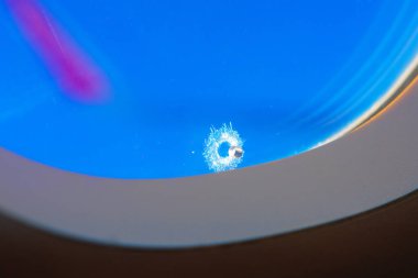 Mavi gökyüzüne karşı uçak penceresinde küçük bir delik. Modern uçak malzemelerinin uçuş esnekliği ve kırılganlığı vurgulandı