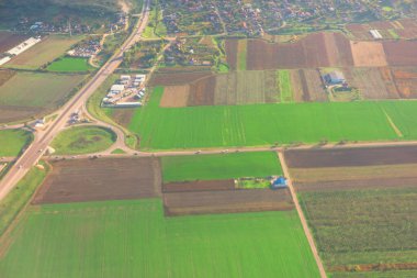 Kırsal alanların havadan görünüşü, tarımsal alanlar, yollar, küçük yerleşim alanları, bölünmüş araziler, çeşitli ekinler, ana yolları bağlayan kavşak, kırsal altyapıyı vurguluyor