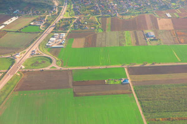 Вид с воздуха на сельскую местность, смесь сельскохозяйственных полей, дорог, маленького поселения, разделенных участков, разнообразных культур, кольцевых соединений основных дорог, освещаются вопросы землепользования и сельской инфраструктуры