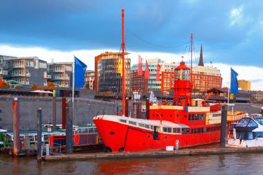  Hamburg ikonik liman alanı, modern mimari ve hareketli gezinti alanları boyunca kenetlenmiş canlı bir kırmızı ışık gemisi. Manzaralı deniz manzarası şehrin deniz cazibesini ve canlı atmosferini yakalıyor.