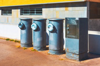 Endüstriyel metal yapılar, havalandırma birimleri ve malzeme kutusu da dahil olmak üzere, sarı ve gri renkli modern bir binanın ön cephesine yerleştirilmiş. Kentsel, endüstriyel ve mimari bir yapıyı yakalar.