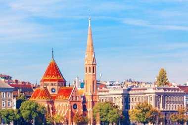 Budapeşte Macaristan 'daki Szilagyi Dezso Meydanı Reform Kilisesi. Diğer tarihi binalar ve yeşil ağaçlarla çevrili yüksek kulesi ve çarpıcı kırmızı kiremitli çatısı olan önemli bir kilisenin bulunduğu şehir manzarası