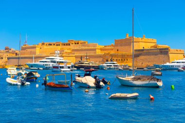 Malta 'daki St. Angelo Kalesi. Kale, limanda demirlemiş modern yat ve tekneler tarafından çerçevelenmiş. Eski dünya cazibesi ve günümüzün deniz aktivitelerinin çarpıcı bir karışımı.
