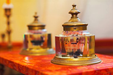 Pirinç kapaklı ve kristal vücutlu zarif antik mürekkep hokkaları parlayan ahşap masaya oturur ve ortam ışığını yansıtır. Karmaşık tasarım ve tarihi cazibe onu klasik projeler ve dekorasyon için mükemmel kılıyor.