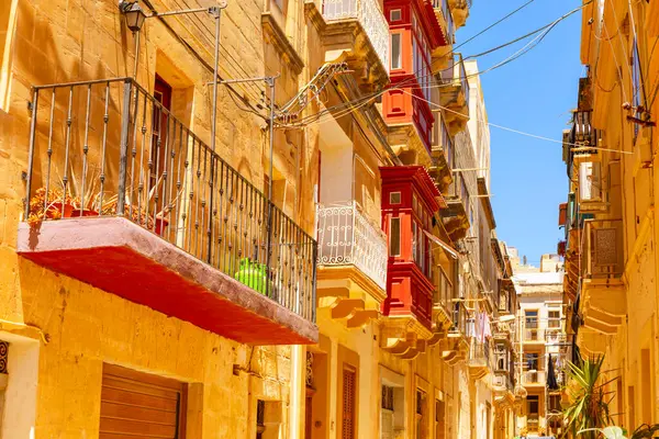 Senglea, Malta 'da günışığı alan dar bir cadde. Geleneksel kireçtaşı binalar ve ahşap balkonlarla dolu. Sıcak tonlar ve karmaşık mimari ayrıntılar tarihi Akdeniz kasabasının cazibesini yakalıyor