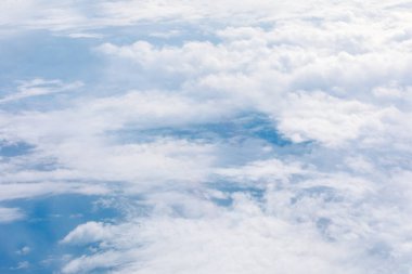 Hava görüntüsü, dingin mavi bir gökyüzünün üzerinde yüzen tüylü beyaz bulutların uçsuz bucaksız genişliğini ortaya çıkarır. Aşağıdaki dünyadan ipuçları içeren ruhani sahne atmosfer teması için mükemmeldir.