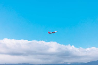 Bulutların üzerinde canlı mavi gökyüzü ile uçan bir uçak. Seyahat, özgürlük ve maceranın özünü yakalar. Havacılık, turizm veya ulaşımla ilgili konular için ideal