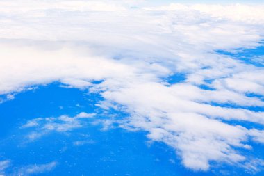 Kabarık beyaz bulutlar, yukarıdan gelen yumuşak güneş ışığıyla aydınlatılarak, sonsuza dek aşağıya doğru uzanıyor. Ufuktaki derin maviden daha açık bir renge geçişler, daha sakin bir hava manzarası yaratır.