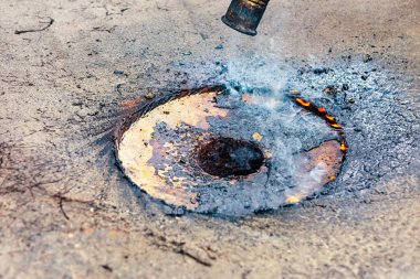 Çatı tamiri, malzemelere kaynak yapmak için ısı uygulaması. Hasarlı çatıyı alevler yalayıp onarıma hazırlıyor.