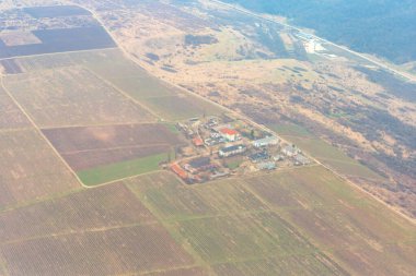 Uçsuz bucaksız tarım arazileri doğal ortamda insan faaliyeti düzeni oluşturuyor. Kırsal alandaki hava perspektifi, tarım alanlarıyla binalar arasındaki etkileşimi vurguluyor.