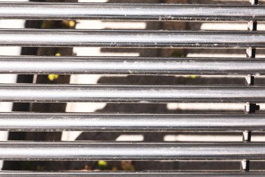 Paralel metal çubuklar, yapılandırılmış ve rafine edilmiş bir tasarım yaratıyor. Metal ızgaranın ayrıntılı görüntüsü pürüzsüz yüzeyi ve hassas çizgileri gösteriyor.