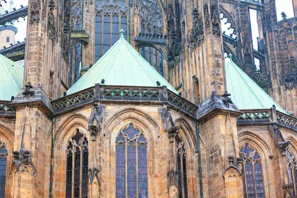 Prag 'daki Aziz Vitus Katedrali' nin detayları. Karmaşık taş işçiliği, büyük vitray pencereleri ve yeşil bakır çatıları olan Gotik katedralde etkileyici bir mimari ve işçilik sergileniyor.