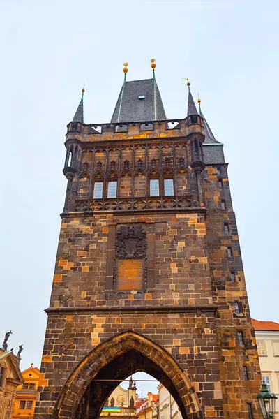 Prag 'dan Charles Köprüsü Kulesi. Prag 'daki tarihi taş kule, sivri kuleleri ve kemerli bir geçidi olan karmaşık Gotik mimari içeriyor.