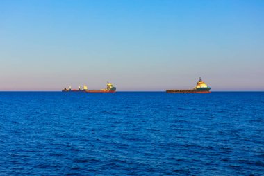 Kargo gemileri okyanusun uçsuz bucaksız genişliğini aşar. Açık denizin sakin manzarası, ufukta süzülen iki gemi.