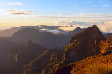 Madeira 'da Pico do Areeiro' nun engebeli tepelerinde altın ışık, dağlık arazide dramatik gölgeler bırakır. Bulutlar gecenin erken saatlerinde canlı gökyüzünün altındaki derin vadilerde sürükleniyor.