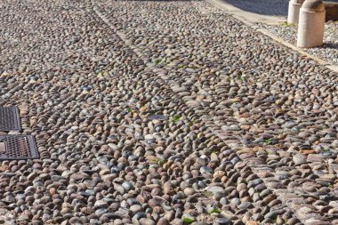 Pürüzsüz, yuvarlak taşlardan yapılmış el yapımı kaldırım deseni. Antik kaldırım taşları, birbirine sıkıca bağlanmış, dayanıklı ve görsel olarak çekici bir yüzey oluşturur. Cobblestone Caddesi, eski kasabada.