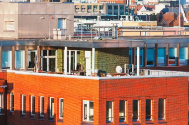 Modern şehir terası, şık dış mobilyaları, uydu anteni ve parlak kırmızı tuğlalı duvarları var. Çağdaş kentsel mimari, şehir yaşamında konfor ve işlevselliği vurguluyor