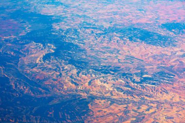 Dağlarla, vadilerle ve çeşitli topoğrafyalarla dolu, sıcak, doğal ışıkla yıkanmış uçsuz bucaksız, çeşitli manzaraların fotoğrafı. Engebeli arazi, coğrafi özellikler ve doğal elementlerin bir karışımı olduğunu gösteriyor.