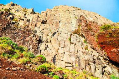 Sert kaya oluşumu, belirgin çokgen kırıklar ve jeolojik katmanlarla karakterize edilmiş sütun bazalt. Antik volkanik aktivite ve hava durumu kayalık yüzeyde görülmektedir.