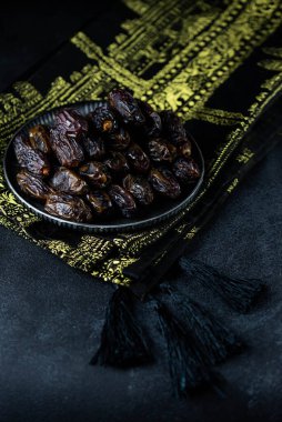 Dates fruit on oriental plate on dark background. Dried organic Superfood