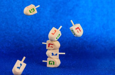 Jewish holiday Hanukkah concept. Wooden dreidel (spinning top) levitation on blue background.