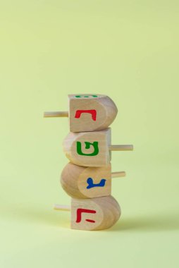 Jewish holiday Hanukkah concept. Wooden dreidel (spinning top) on yellow background.