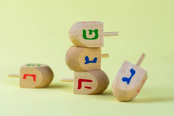 Jewish holiday Hanukkah concept. Wooden dreidel (spinning top) on yellow background.
