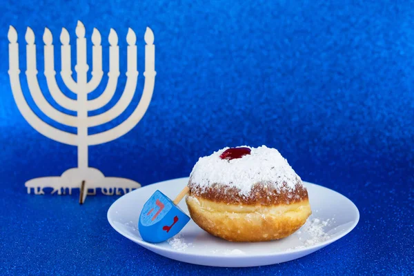 Jewish holiday Hanukkah concept. Menorah - traditional candelabrum or hanukkiah, donut sufganiyot and wooden dreidel - spinning top