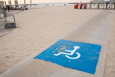 Disability sign and path road for wheel chair on the sea beach. Sand beach places for people with disabilities.