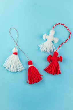 Traditional Martisor - symbol of holiday 1 March, Martenitsa, Baba Marta, beginning of spring and seasons changing in Romania, Bulgaria, Moldova. Greeting and post card for holidays. Blue background.