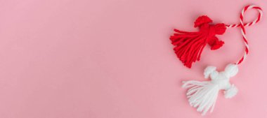 Traditional Martisor - symbol of holiday 1 March, Martenitsa, Baba Marta, beginning of spring and seasons changing in Romania, Bulgaria, Moldova. Greeting and post card for holidays. Pink background. Banner