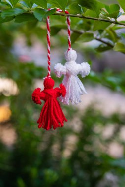 Traditional Martisor on green tree branch - symbol of 1 March, Martenitsa, Baba Marta, beginning of spring and seasons changing in Romania, Bulgaria, Moldova. Greeting and post card for holidays.