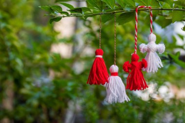 Traditional Martisor on green tree branch - symbol of 1 March, Martenitsa, Baba Marta, beginning of spring and seasons changing in Romania, Bulgaria, Moldova. Greeting and post card for holidays.