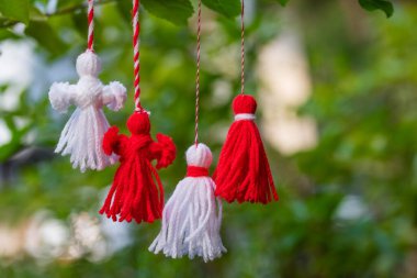 Traditional Martisor on green tree branch - symbol of 1 March, Martenitsa, Baba Marta, beginning of spring and seasons changing in Romania, Bulgaria, Moldova. Greeting and post card for holidays.