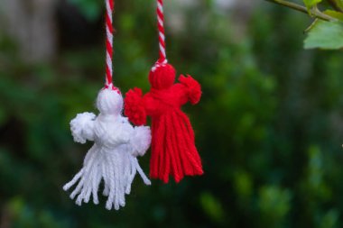 Traditional Martisor on green tree branch - symbol of 1 March, Martenitsa, Baba Marta, beginning of spring and seasons changing in Romania, Bulgaria, Moldova. Greeting and post card for holidays.