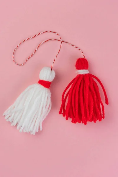 Traditional Martisor - symbol of holiday 1 March, Martenitsa, Baba Marta, beginning of spring and seasons changing in Romania, Bulgaria, Moldova. Greeting and post card for holidays. Pink background.