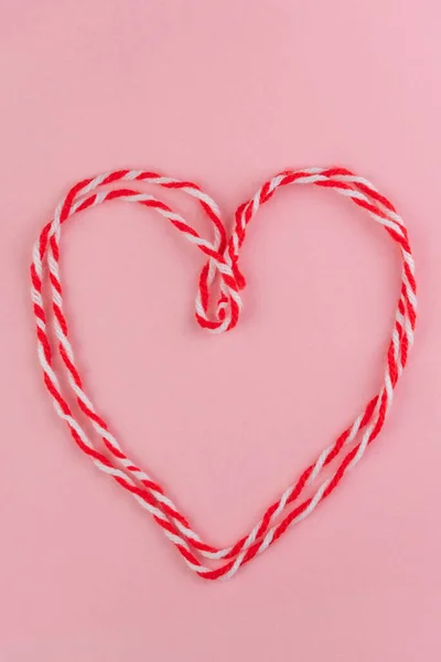 Traditional Martisor - symbol of holiday 1 March, Martenitsa, Baba Marta, beginning of spring and seasons changing in Romania, Bulgaria, Moldova. Greeting and post card for holidays. Pink background.