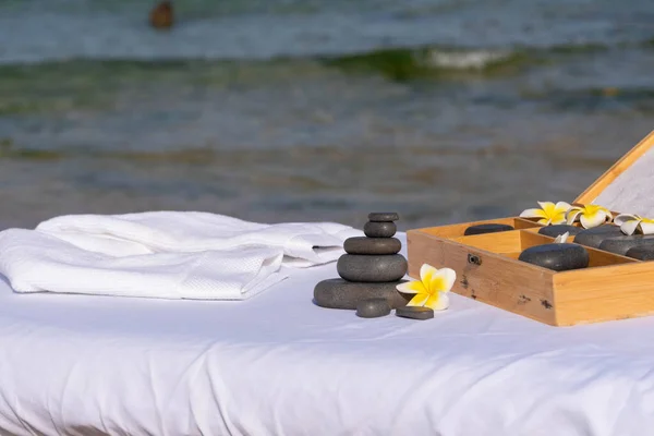 由专业按摩师为在热带按摩浴过程中放松而准备的按摩按摩 在海边的按摩台上用热带花按摩热身 — 图库照片