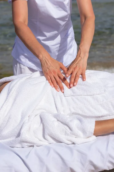 在海滩上的热带按摩浴中放松的女人在海边的按摩床上 专业按摩师提供颈部 脸部及胸腔水疗服务 — 图库照片