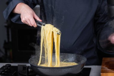 Profesyonel aşçılar İtalyan Capellini spagetti makarnası yapıyorlar modern mutfak ocağında kaynar suda tava tenceresinde. Sıcak yemek buharı..