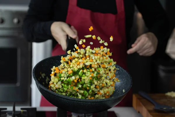 Chef cook roasts vegetables with seafood in wok pan on gas stove. Flying vegetable food levitation in motion, skillfully tossed by the chef hand. Airborne creative culinary expertise.