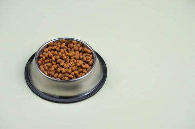 Metal kasedeki kahverengi kedi ya da köpek maması üst görüntüyü izole etti. Besleyici, sağlıklı, evcil hayvan mamaları etrafa saçılmış, düşmüş ve kaseyi şelaleye çevirmiş. Kuru kedi veya köpek maması bir kaseden dökülür..