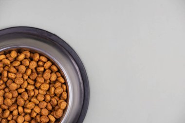 Metal kasedeki kahverengi kedi ya da köpek maması üst görüntüyü izole etti. Besleyici, sağlıklı, evcil hayvan mamaları etrafa saçılmış, düşmüş ve kaseyi şelaleye çevirmiş. Kuru kedi veya köpek maması bir kaseden dökülür..