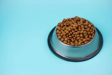 Metal kasedeki kahverengi kedi ya da köpek maması üst görüntüyü izole etti. Besleyici, sağlıklı, evcil hayvan mamaları etrafa saçılmış, düşmüş ve kaseyi şelaleye çevirmiş. Kuru kedi veya köpek maması bir kaseden dökülür..