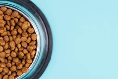 Metal kasedeki kahverengi kedi ya da köpek maması üst görüntüyü izole etti. Besleyici, sağlıklı, evcil hayvan mamaları etrafa saçılmış, düşmüş ve kaseyi şelaleye çevirmiş. Kuru kedi veya köpek maması bir kaseden dökülür..