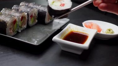 Japon yemeklerini yiyen çubuklarla ellerini yaklaştır. Geleneksel Asya dürümleri. Sebzeli ve ton balıklı Maki suşi.