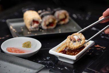 Japon yemeklerini yiyen çubuklarla ellerini yaklaştır. Geleneksel Asya dürümleri. Sebzeli ve ton balıklı Maki suşi.