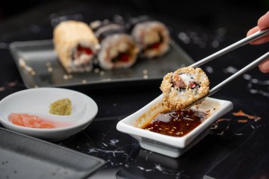 Japon yemeklerini yiyen çubuklarla ellerini yaklaştır. Geleneksel Asya dürümleri. Sebzeli ve ton balıklı Maki suşi.